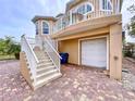 Tan two-story house with white trim, stairs, and a brick driveway at 4178 Des Prez Ct, Hernando Beach, FL 34607