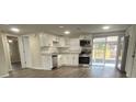 Modern kitchen featuring white cabinets, stainless steel appliances, and wood-look floors at 7318 Dianne Dr, New Port Richey, FL 34652