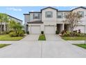 Two story townhome with gray exterior, two-car garage, and landscaping at 7230 Sweet Alyssum Ct, Tampa, FL 33619