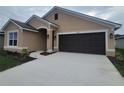 Tan house with a brown garage door and landscaped yard at 13278 Ogden Glade Rd, Dade City, FL 33525