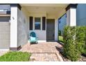 Inviting front porch with a teal chair and brick flooring at 18015 Fenders Way, Land O Lakes, FL 34638