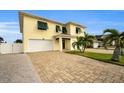 Two-story house with a yellow facade, white garage doors, and palm trees at 11325 5Th E St, Treasure Island, FL 33706