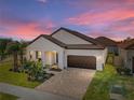 One-story house with brown roof and landscaping at sunset at 16931 Scuba Crest St, Wimauma, FL 33598