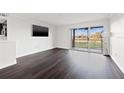 Living room with wood-look floors, balcony access, and golf course view at 2400 Feather Sound Dr # 127, Clearwater, FL 33762