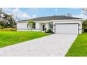 White house with gray roof, paved driveway, and grassy yard at 189 Statler St, Port Charlotte, FL 33954