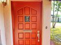 Close-up of the red front door featuring a decorative glass insert and a brushed metal handle at 6700 Turner N St, St Petersburg, FL 33702