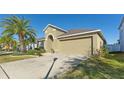 Tan house exterior with a red door and two-car garage at 12410 Ballentrae Forest Dr, Riverview, FL 33579