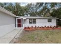 Newly renovated home with gray and white exterior, landscaped yard, and a red door at 11592 110Th Ter, Seminole, FL 33778