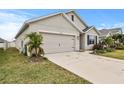 Tan house with a two-car garage and a neatly landscaped lawn at 17019 Avon Dive Ln, Wimauma, FL 33598