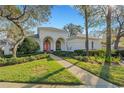 White house with pink door, landscaped yard, and walkway at 2850 Deer Run, Tarpon Springs, FL 34688