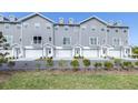 Row of gray townhomes with white garage doors and landscaping at 5736 Biscayne Ct # 3, New Port Richey, FL 34652