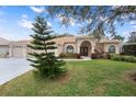 House exterior showcasing landscaping and a three-car garage at 2342 Edelweiss Loop, Trinity, FL 34655