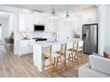 Modern white kitchen with island, stainless steel appliances, and light wood floors at 12269 New Tranquility Path, Venice, FL 34293