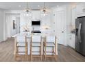Modern white kitchen with island, stainless steel appliances, and light wood floors at 12269 New Tranquility Path, Venice, FL 34293