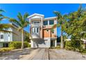 Three-story house with orange exterior, two-car garage, and landscaped yard at 206 Church Ave, Bradenton Beach, FL 34217