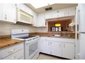 White kitchen with wood countertops and appliances at 1485 Halsey Dr # 101, Dunedin, FL 34698