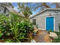 Charming side yard with brick path, lush foliage, and blue door at 2886 Bay Shore Dr, Safety Harbor, FL 34695