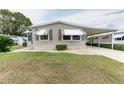 Tan mobile home with carport, landscaping, and paved driveway at 36900 Grace Ave, Zephyrhills, FL 33542