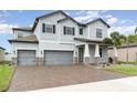 Two-story house with gray siding, stone accents, and a three-car garage at 13513 White Sapphire Rd, Riverview, FL 33579