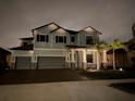 Two-story house with lights, gray siding, and a three-car garage at 13513 White Sapphire Rd, Riverview, FL 33579