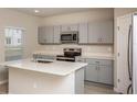 Modern kitchen with gray cabinets, quartz countertops, and stainless steel appliances at 2049 Stillview Pass, Zephyrhills, FL 33541