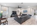 Living area with gray sectional sofa, large TV, and wood flooring at 34432 Wynthorne Pl, Wesley Chapel, FL 33545