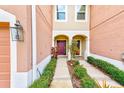 Townhome entry with a burgundy door and neatly landscaped walkway at 26519 Castleview Way, Wesley Chapel, FL 33544