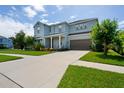 Two-story light blue house with a gray roof, landscaping, and driveway at 3238 Mela Ct, Holiday, FL 34691