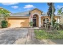 Tan one-story house with a two-car garage and manicured landscaping at 12308 Adventure Dr, Riverview, FL 33579