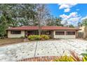 Single-story home with red tile roof, spacious driveway, and lush landscaping at 1545 Park N St, St Petersburg, FL 33710