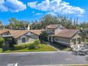 Exterior view featuring a detached garage, well-kept lawn, lush landscaping, and charming architectural details at 1673 Nash Ct, Dunedin, FL 34698