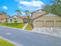 Three car garage and exterior view of tan colored villa at 1673 Nash Ct, Dunedin, FL 34698