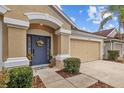 Tan one story house with a blue front door and two car garage at 5310 Algerine Pl, Wesley Chapel, FL 33544