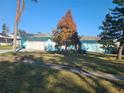 Cute light blue home with palm trees and a well-manicured lawn at 1279 Dinnerbell E Ln, Dunedin, FL 34698