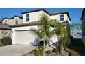 Two-story house with white exterior, two-car garage, palm trees, and lake view at 4410 Summer Savory St, Tampa, FL 33619