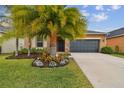 Tan house with dark gray garage door and lush landscaping at 11804 Valhalla Woods Dr, Riverview, FL 33579