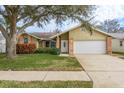 Tan house with brick accents, green lawn, and a white garage door at 3048 Orchard Dr, Palm Harbor, FL 34684