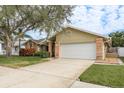 Tan house with a large tree, green lawn, and a white garage door at 3048 Orchard Dr, Palm Harbor, FL 34684