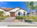 Single-story home's front exterior showcasing a wooden garage door and garden at 5328 Stoic Vale Dr, Wimauma, FL 33598