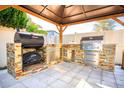 Outdoor kitchen with grill, smoker, and stone countertops at 7932 Pelican Reed Cir, Wesley Chapel, FL 33545