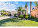 Two-story house with a beige exterior, lush landscaping, and palm trees at 1613 Sand Key Estates Ct, Clearwater, FL 33767
