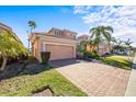Two-story house with a beige exterior, a two-car garage, and a brick driveway at 1613 Sand Key Estates Ct, Clearwater, FL 33767