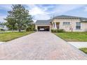 Brick driveway and garage of a tan house at 27325 Mistflower Dr, Wesley Chapel, FL 33544