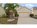 Front yard view of charming house with palm trees and two-car garage at 12017 Gillingham Harbor Ln, Gibsonton, FL 33534