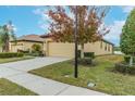 Side view of a tan house with a two-car garage and lush green landscaping at 417 Brandywine Falls Ct, Apollo Beach, FL 33572