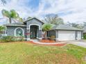 Gray house with two-car garage, landscaped yard, and stained-glass window at 23635 Oakside Blvd, Lutz, FL 33559