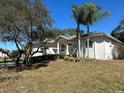 White single story house with palm trees and lush landscaping at 3040 Sheppards Crook Ct, Holiday, FL 34691