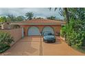 Two-car garage with a long driveway and tropical landscaping at 263 Overbrook E St, Largo, FL 33770