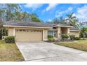 Tan house with a two-car garage and nicely landscaped lawn at 599 Centerwood Dr, Tarpon Springs, FL 34688