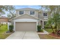 Two-story house with beige exterior, two-car garage, and landscaped yard at 10525 Lucaya Dr, Tampa, FL 33647